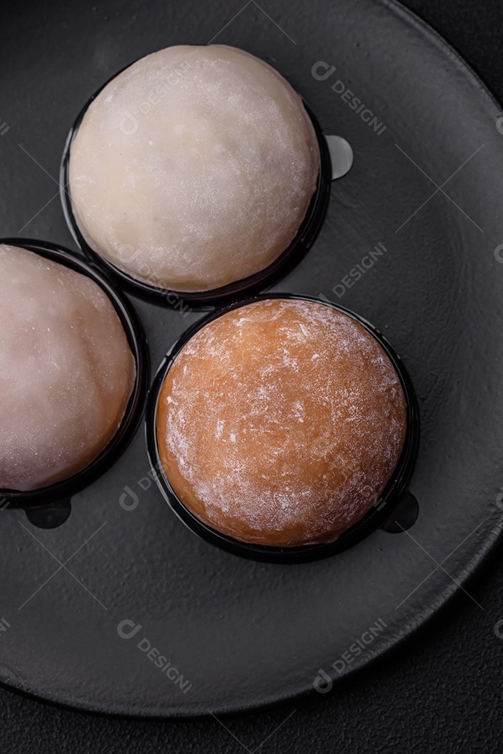 Deliciosa sobremesa mochi doce com coberturas em um fundo escuro de concreto. Sobremesa asiática vegetariana nutritiva