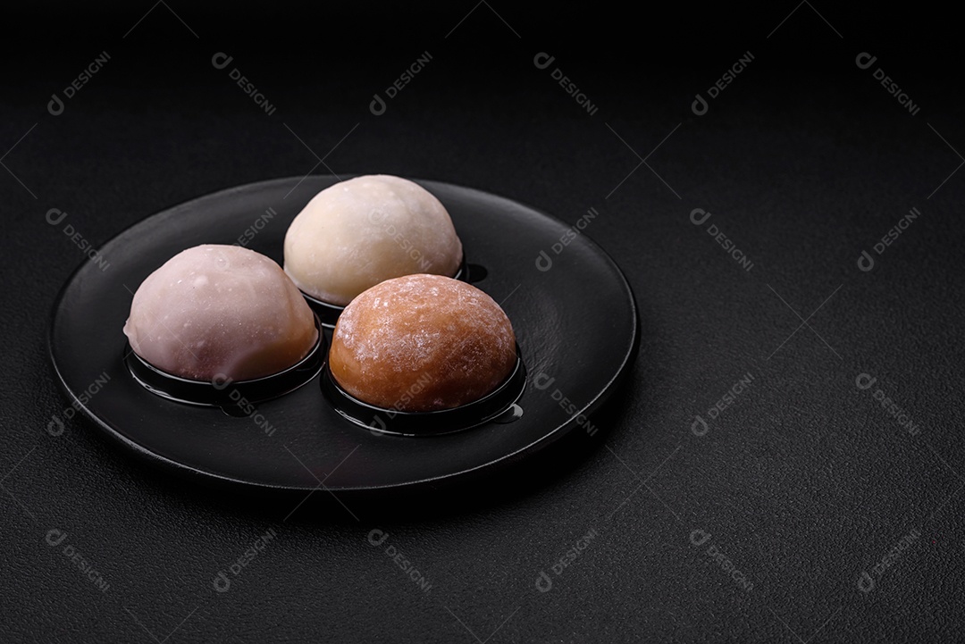 Deliciosa sobremesa mochi doce com coberturas em um fundo escuro de concreto. Sobremesa asiática vegetariana nutritiva