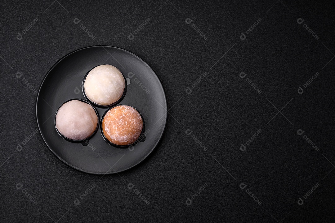 Deliciosa sobremesa mochi doce com coberturas em um fundo escuro de concreto. Sobremesa asiática vegetariana nutritiva