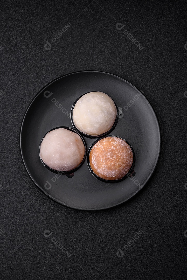 Deliciosa sobremesa mochi doce com coberturas em um fundo escuro de concreto. Sobremesa asiática vegetariana nutritiva