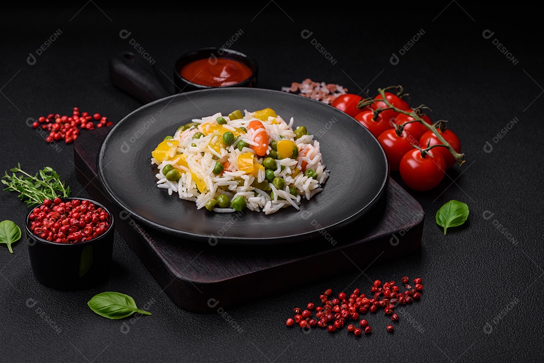 Delicioso arroz cozido branco fresco com vegetais cenouras, pimentões e feijões de espargos em uma placa cerâmica sobre um fundo escuro de concreto