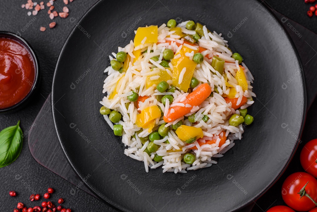 Delicioso arroz cozido branco fresco com vegetais cenouras, pimentões e feijões de espargos em uma placa cerâmica sobre um fundo escuro de concreto