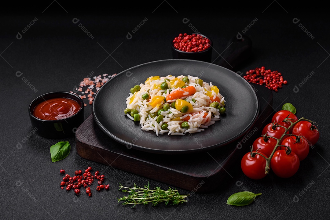 Delicioso arroz cozido branco fresco com vegetais cenouras, pimentões e feijões de espargos em uma placa cerâmica sobre um fundo escuro de concreto