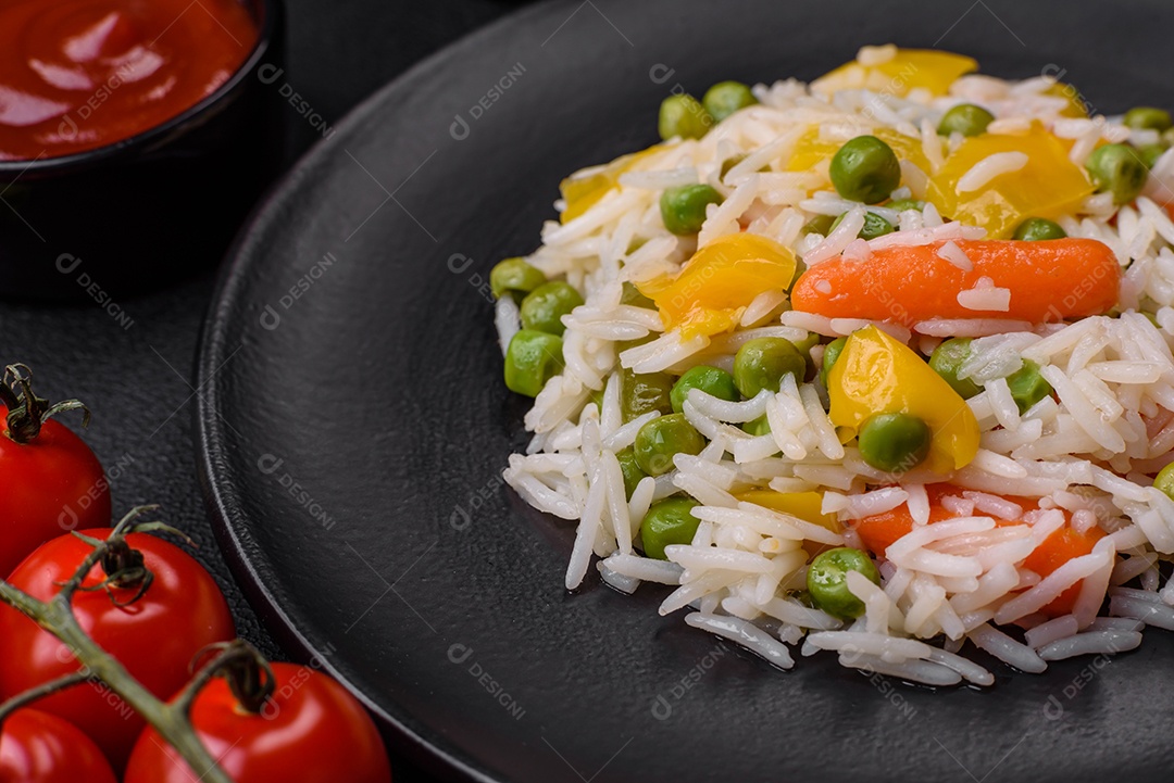 Delicioso arroz cozido branco fresco com vegetais cenouras, pimentões e feijões de espargos em uma placa cerâmica sobre um fundo escuro de concreto