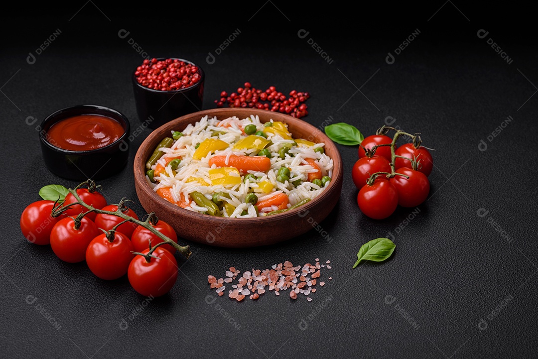 Delicioso arroz cozido branco fresco com vegetais cenouras, pimentões e feijões de espargos em uma placa cerâmica sobre um fundo escuro de concreto