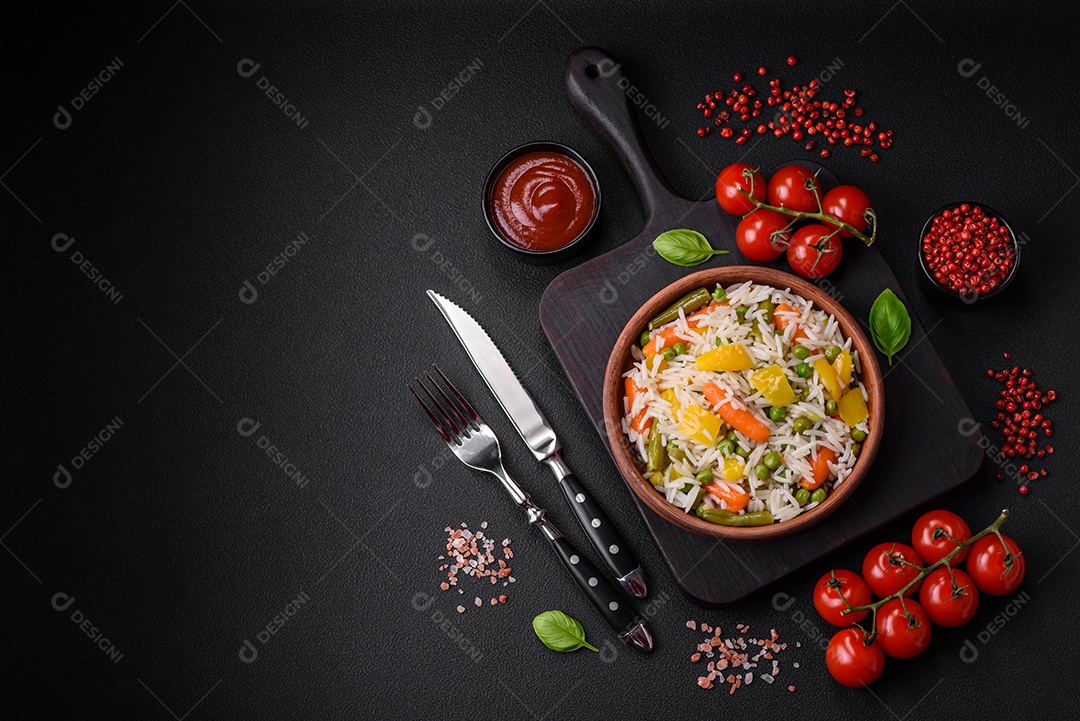Delicioso arroz cozido branco fresco com vegetais cenouras, pimentões e feijões de espargos em uma placa cerâmica sobre um fundo escuro de concreto