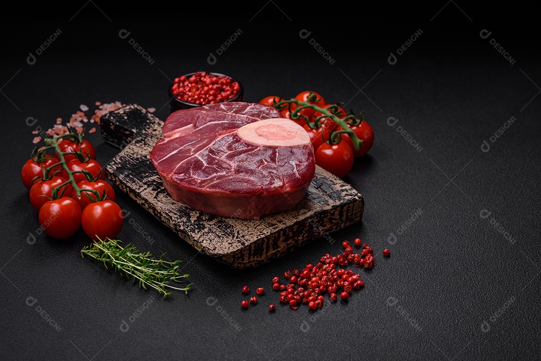Bife cru fresco com osso ou ossobuco com sal, especiarias e ervas em fundo escuro de concreto