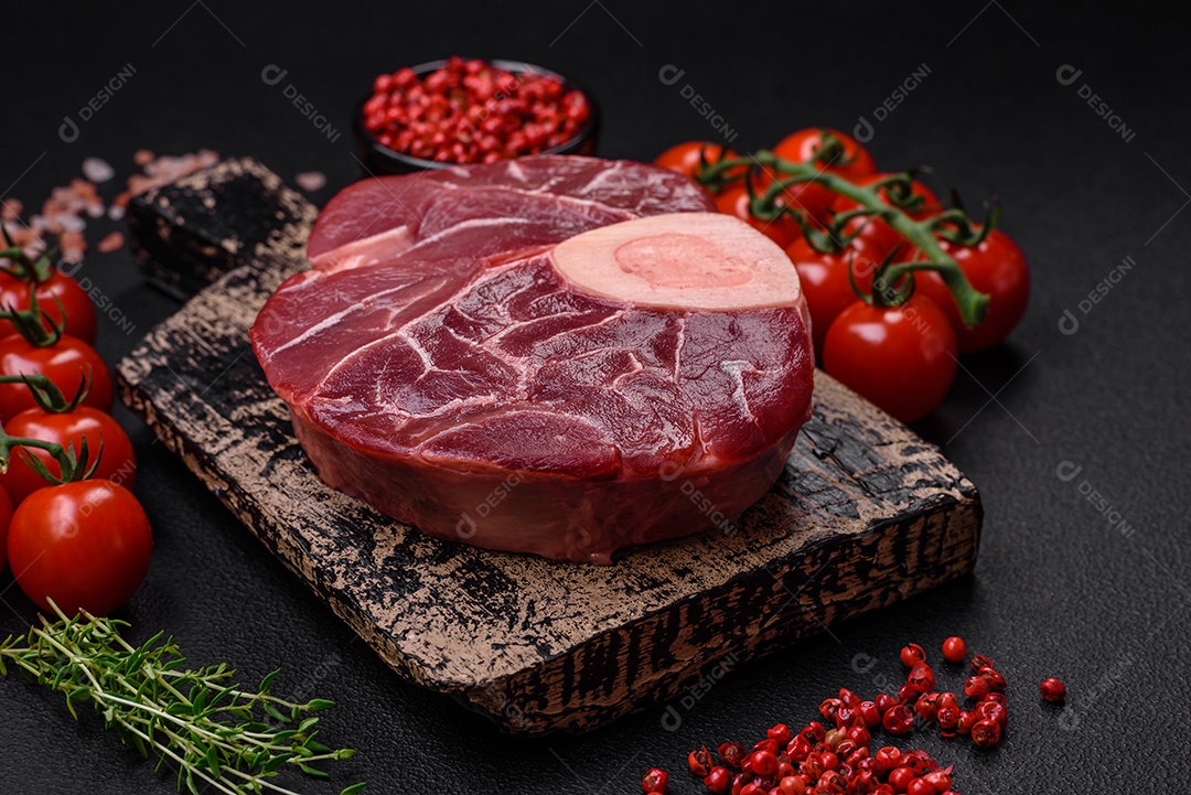 Bife cru fresco com osso ou ossobuco com sal, especiarias e ervas em fundo escuro de concreto