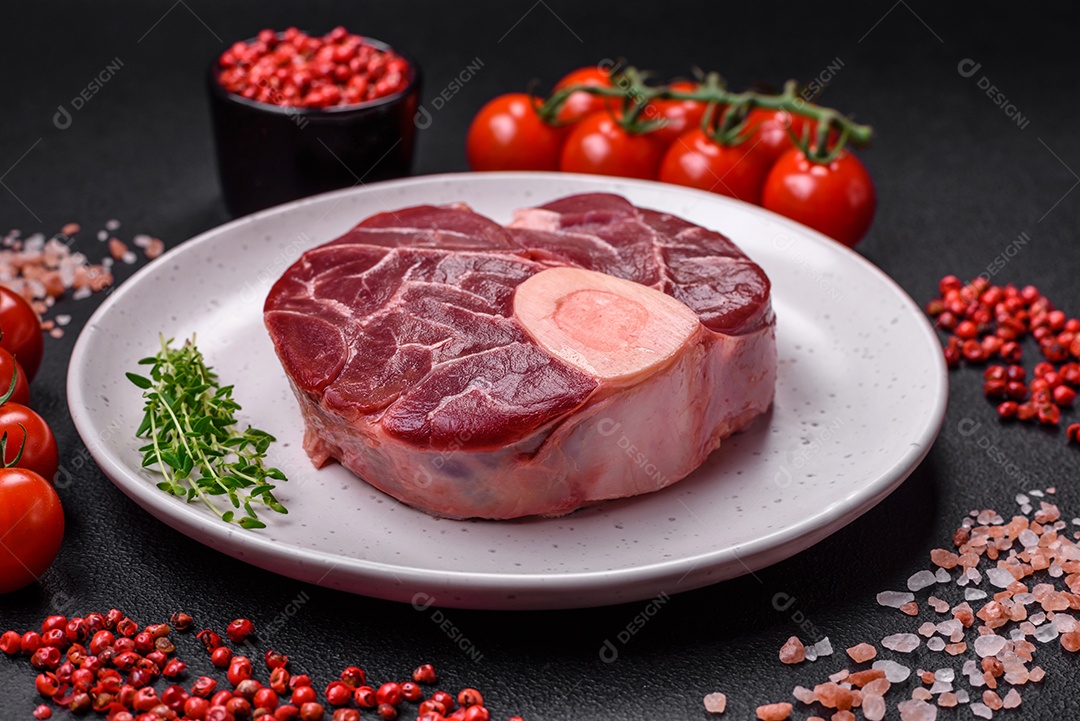 Bife cru fresco com osso ou ossobuco com sal, especiarias e ervas em fundo escuro de concreto