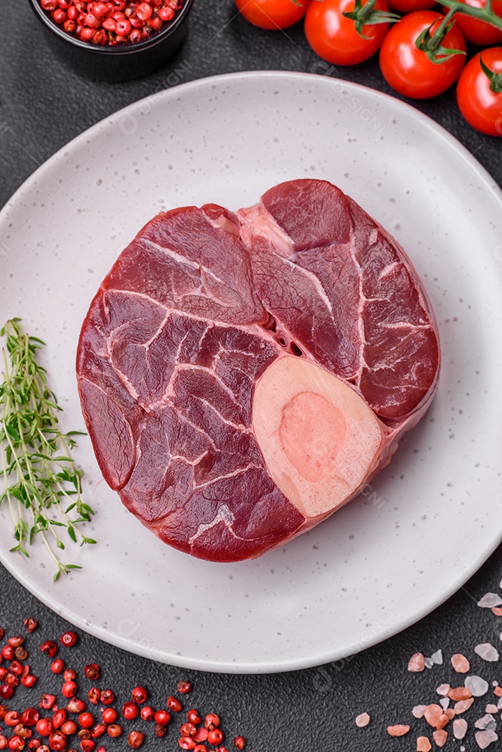 Bife cru fresco com osso ou ossobuco com sal, especiarias e ervas em fundo escuro de concreto