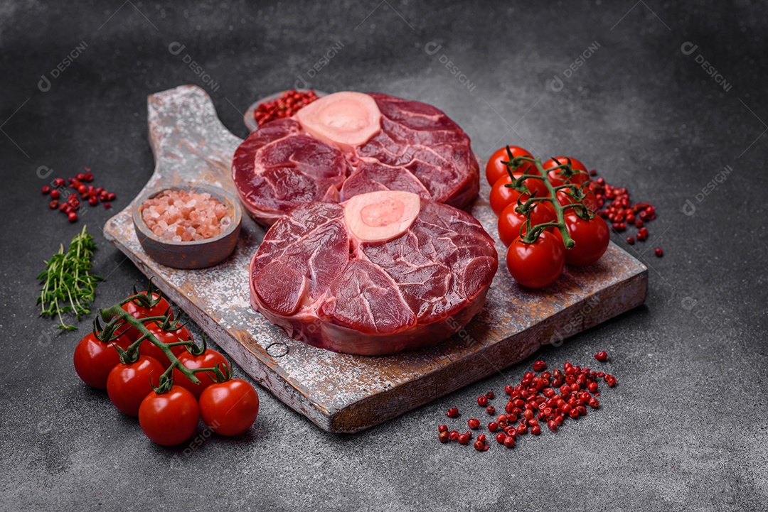 Bife cru fresco com osso ou ossobuco com sal, especiarias e ervas em fundo escuro de concreto