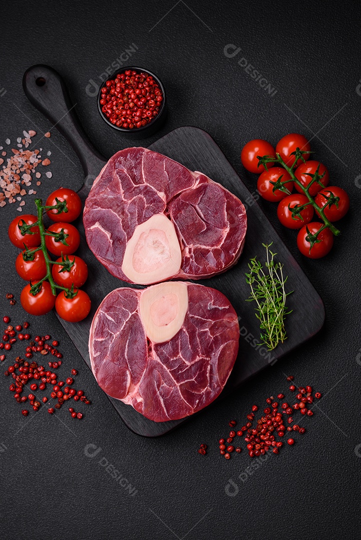 Bife cru fresco com osso ou ossobuco com sal, especiarias e ervas em fundo escuro de concreto