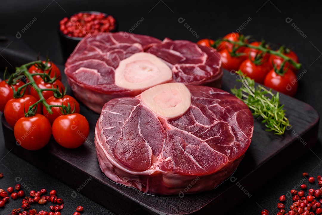 Bife cru fresco com osso ou ossobuco com sal, especiarias e ervas em fundo escuro de concreto