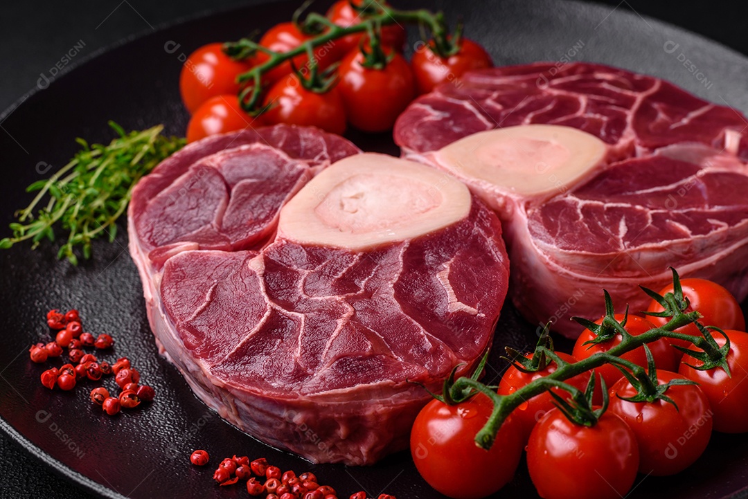 Bife cru fresco com osso ou ossobuco com sal, especiarias e ervas em fundo escuro de concreto