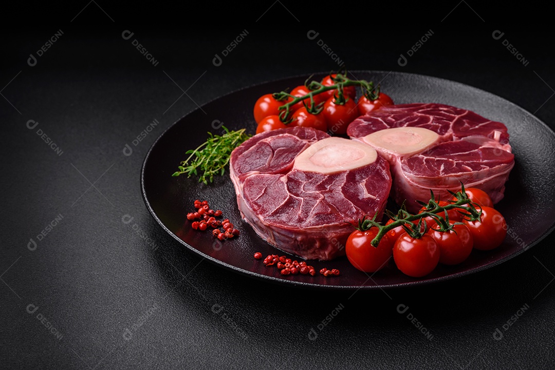 Bife cru fresco com osso ou ossobuco com sal, especiarias e ervas em fundo escuro de concreto