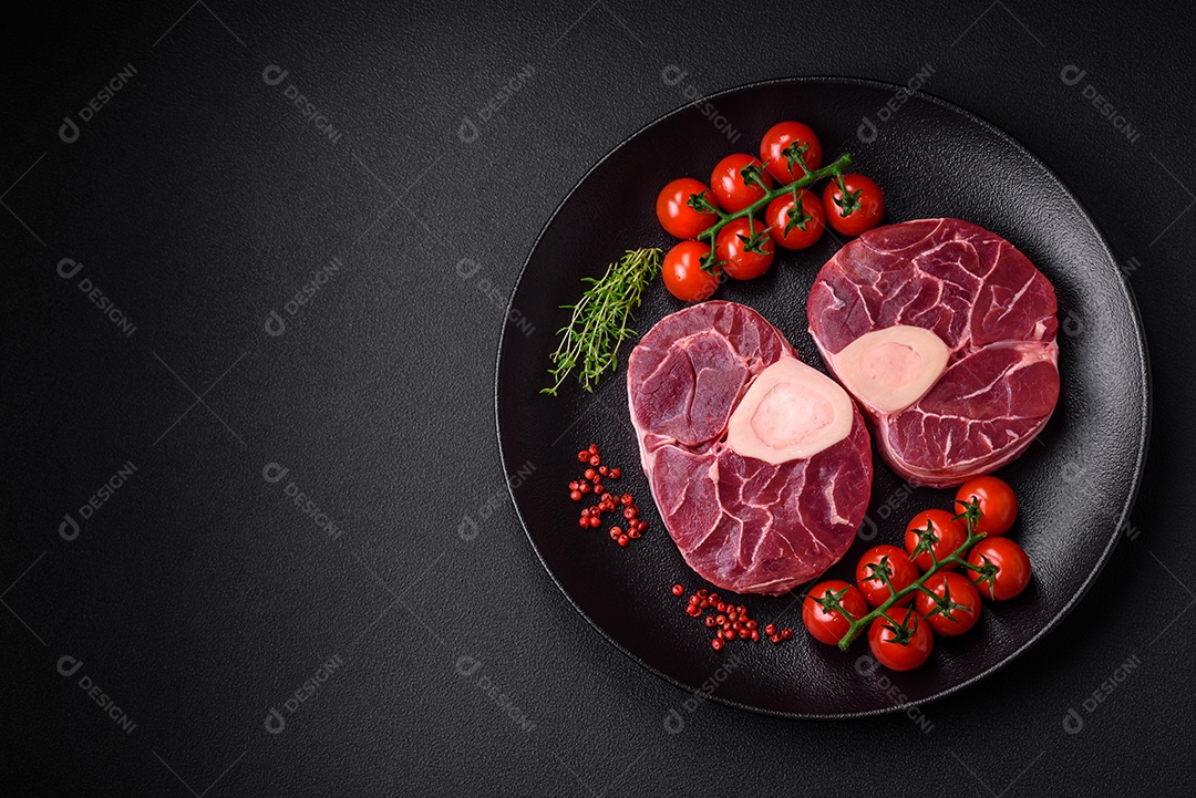 Bife cru fresco com osso ou ossobuco com sal, especiarias e ervas em fundo escuro de concreto