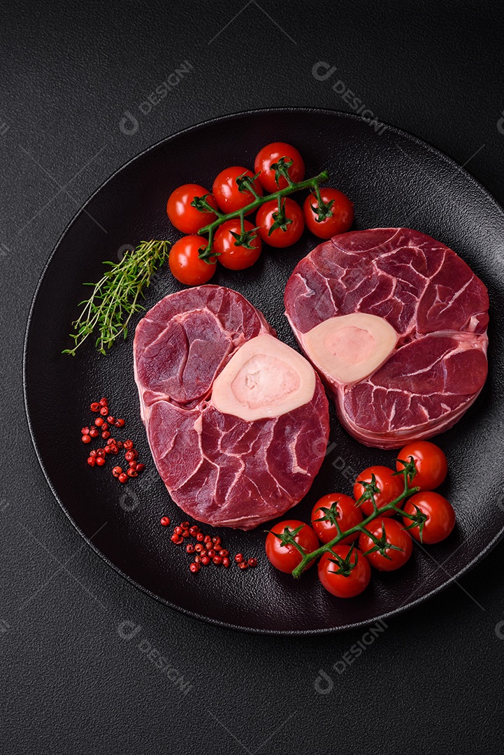 Bife cru fresco com osso ou ossobuco com sal, especiarias e ervas em fundo escuro de concreto
