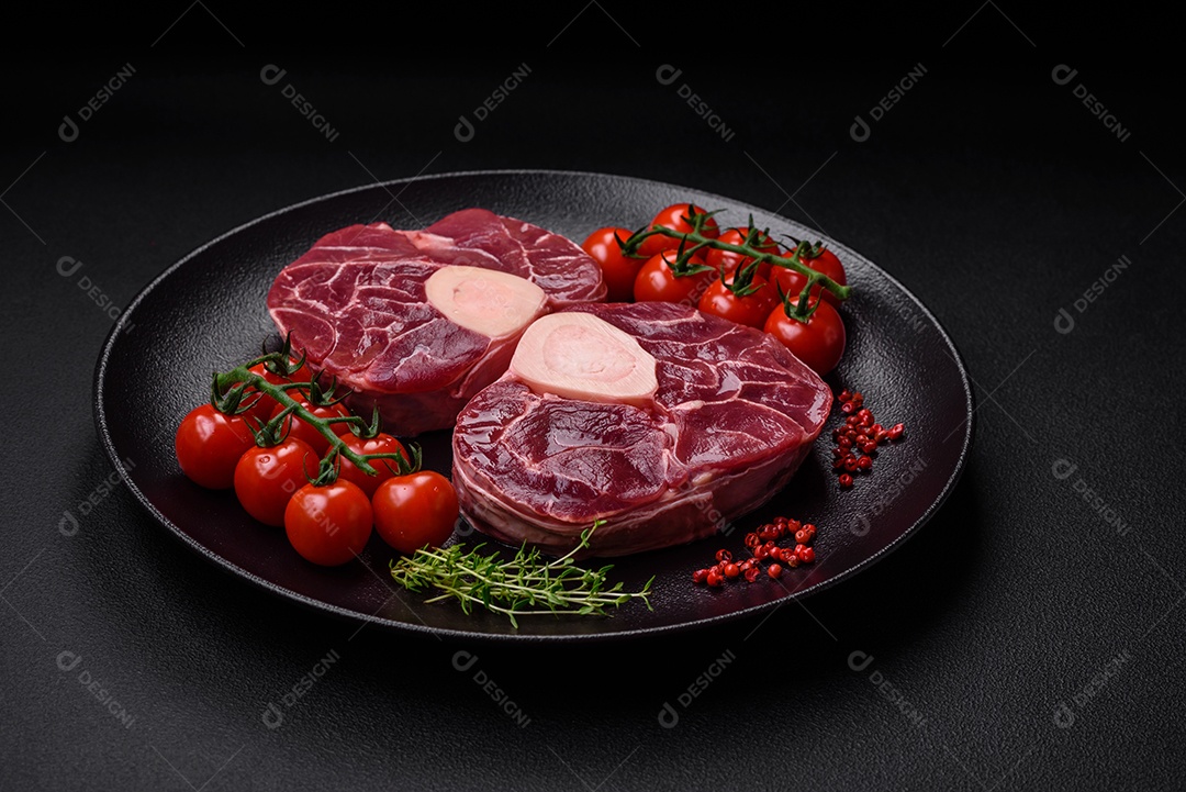 Bife cru fresco com osso ou ossobuco com sal, especiarias e ervas em fundo escuro de concreto