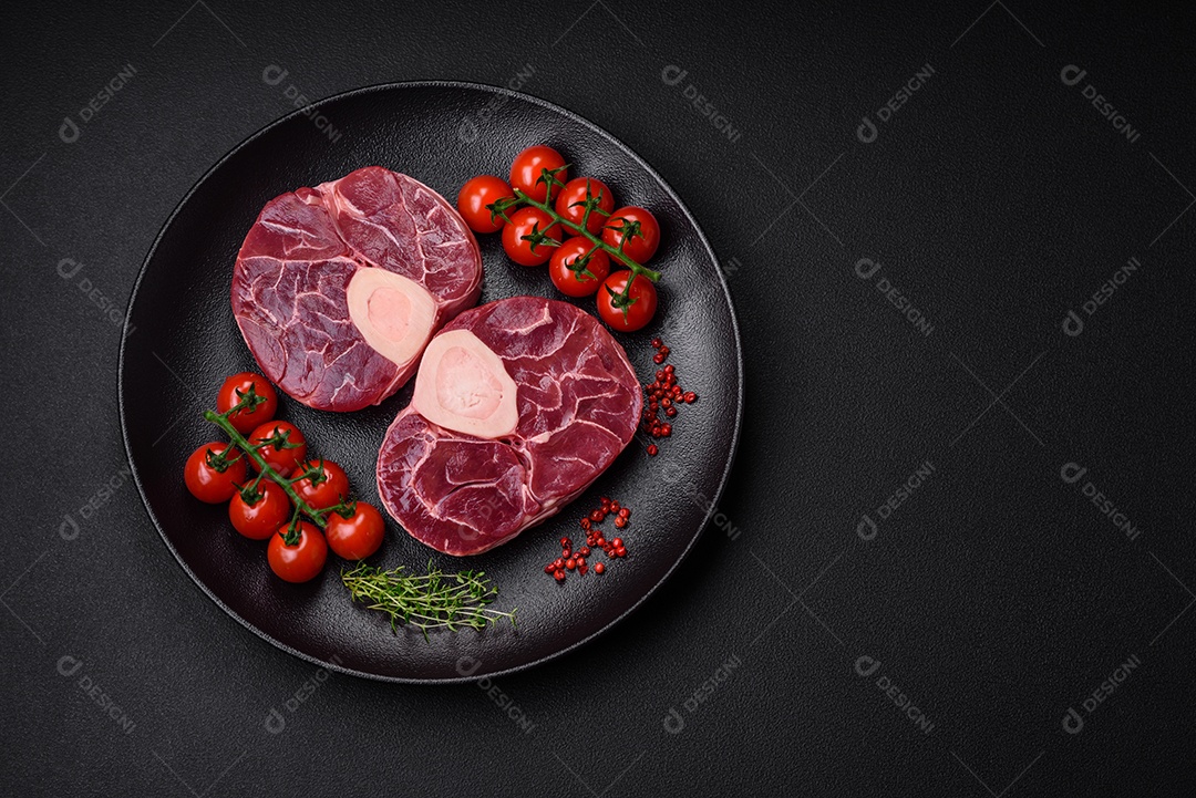 Bife cru fresco com osso ou ossobuco com sal, especiarias e ervas em fundo escuro de concreto