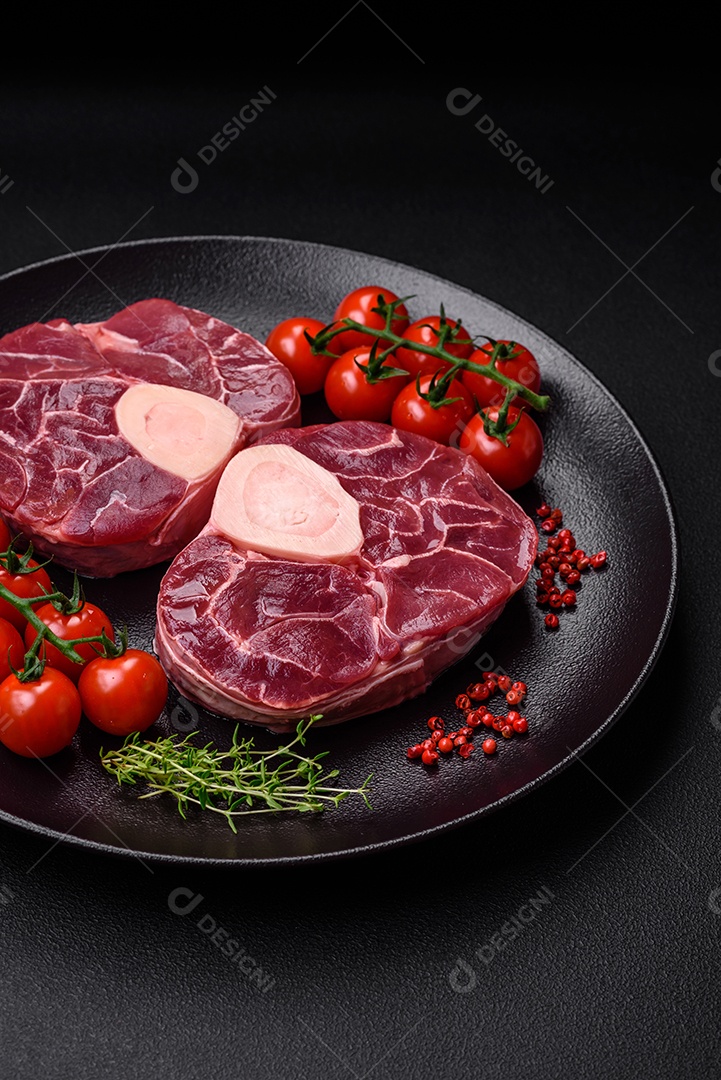 Bife cru fresco com osso ou ossobuco com sal, especiarias e ervas em fundo escuro de concreto