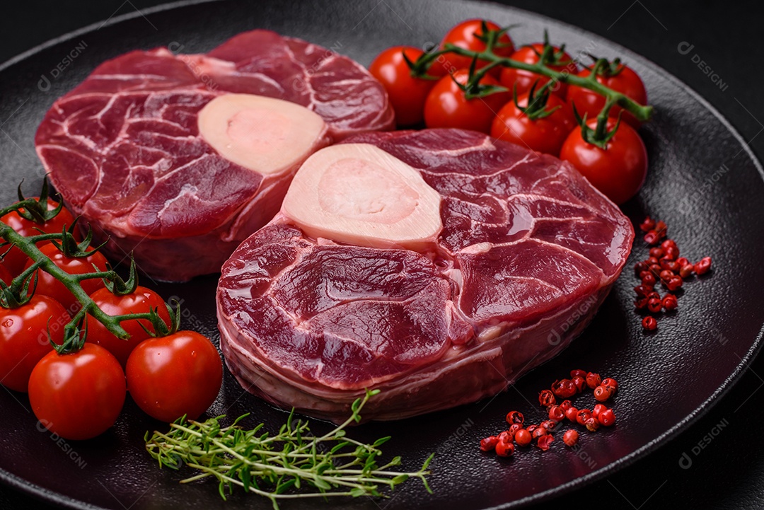 Bife cru fresco com osso ou ossobuco com sal, especiarias e ervas em fundo escuro de concreto