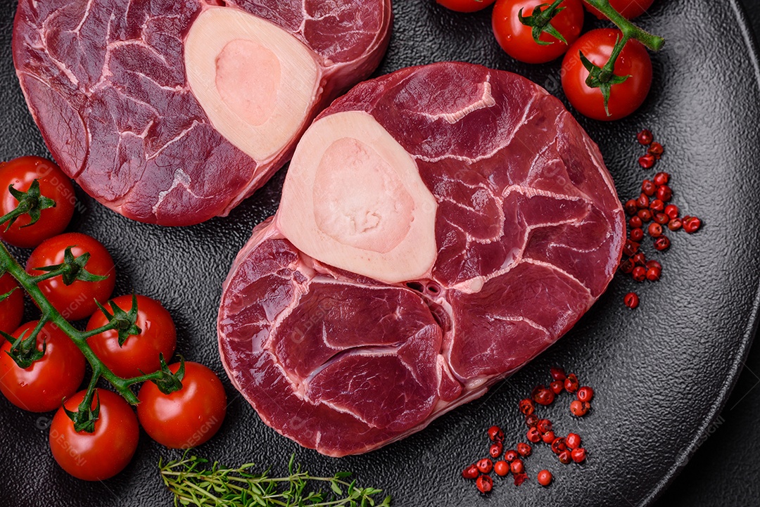 Bife cru fresco com osso ou ossobuco com sal, especiarias e ervas em fundo escuro de concreto