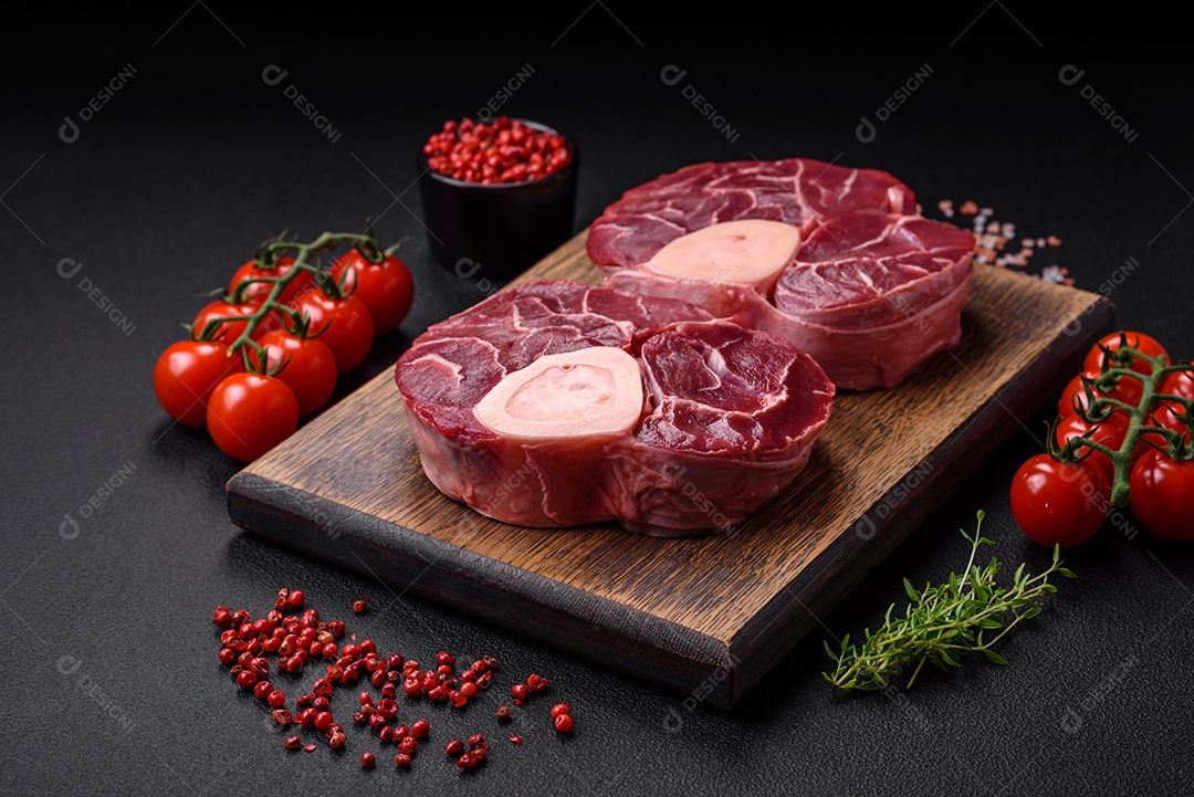 Bife cru fresco com osso ou ossobuco com sal, especiarias e ervas em fundo escuro de concreto