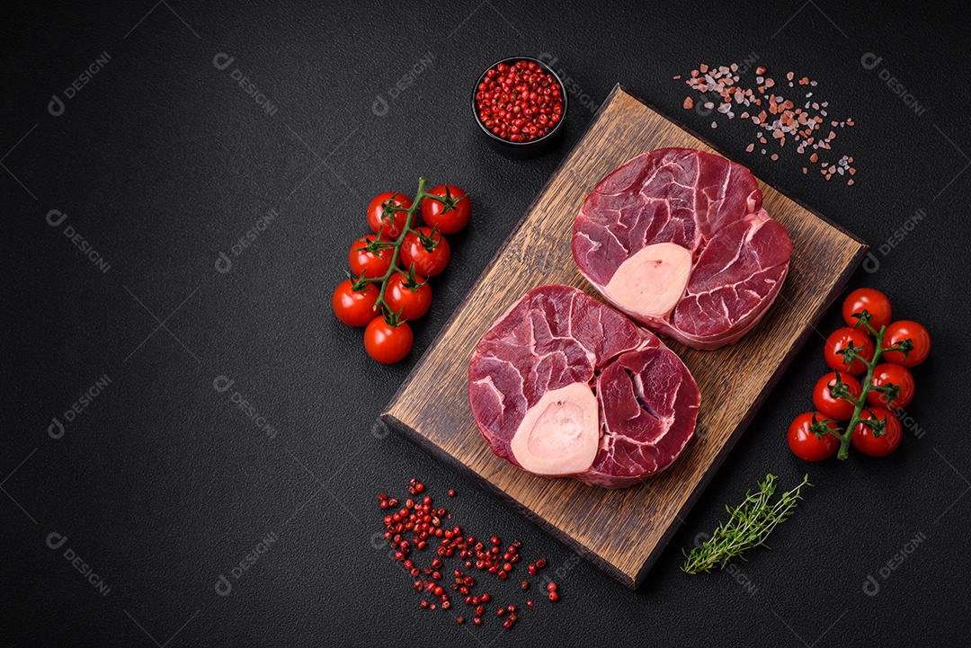 Bife cru fresco com osso ou ossobuco com sal, especiarias e ervas em fundo escuro de concreto