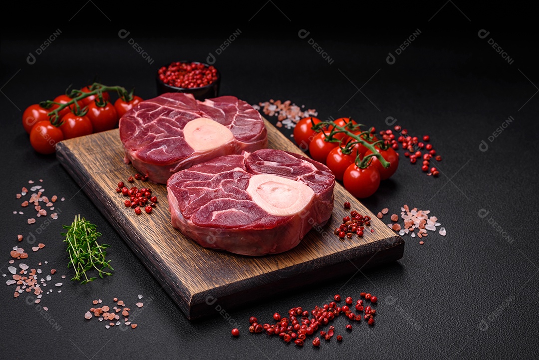 Bife cru fresco com osso ou ossobuco com sal, especiarias e ervas em fundo escuro de concreto