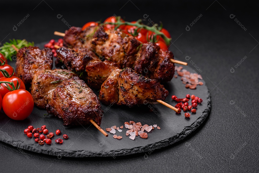 Deliciosos espetos de frango, peru ou porco grelhados com sal, especiarias e ervas no fogo sobre um fundo escuro de concreto