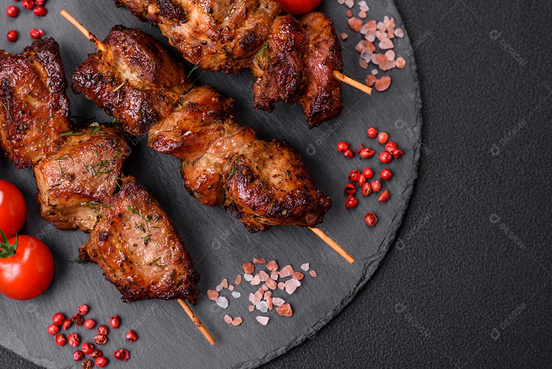 Deliciosos espetos de frango, peru ou porco grelhados com sal, especiarias e ervas no fogo sobre um fundo escuro de concreto