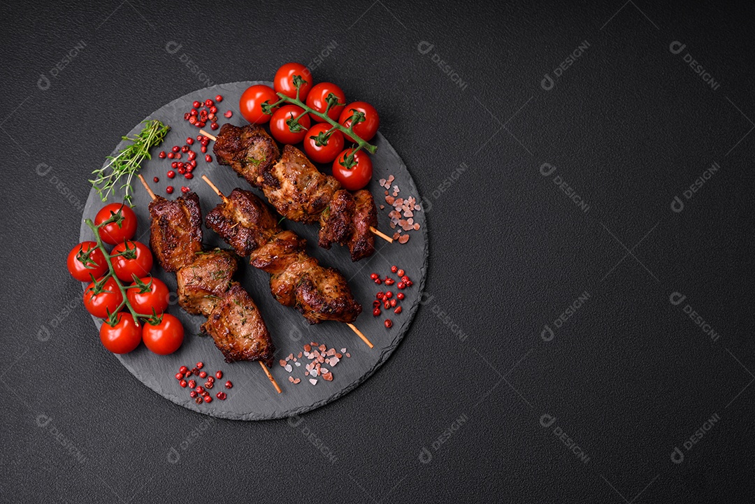 Deliciosos espetos de frango, peru ou porco grelhados com sal, especiarias e ervas no fogo sobre um fundo escuro de concreto