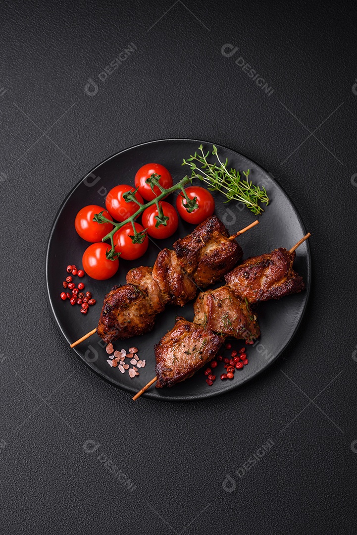 Deliciosos espetos de frango, peru ou porco grelhados com sal, especiarias e ervas no fogo sobre um fundo escuro de concreto