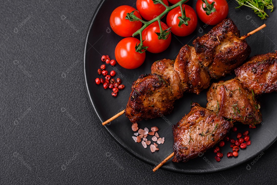 Deliciosos espetos de frango, peru ou porco grelhados com sal, especiarias e ervas no fogo sobre um fundo escuro de concreto