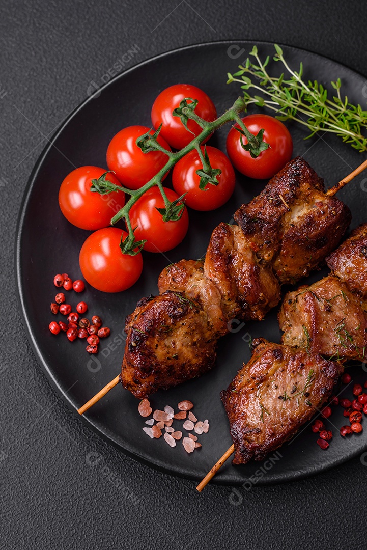 Deliciosos espetos de frango, peru ou porco grelhados com sal, especiarias e ervas no fogo sobre um fundo escuro de concreto