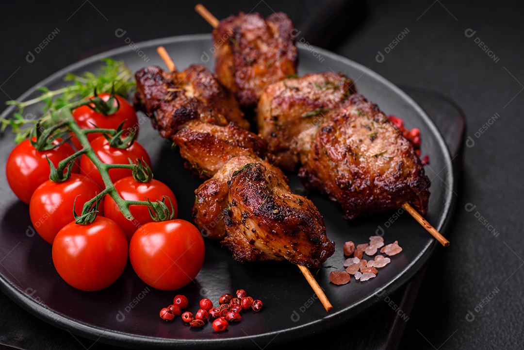 Deliciosos espetos de frango, peru ou porco grelhados com sal, especiarias e ervas no fogo sobre um fundo escuro de concreto