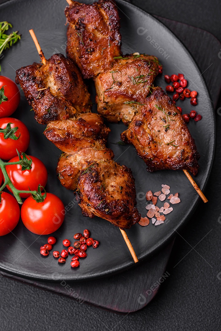 Deliciosos espetos de frango, peru ou porco grelhados com sal, especiarias e ervas no fogo sobre um fundo escuro de concreto