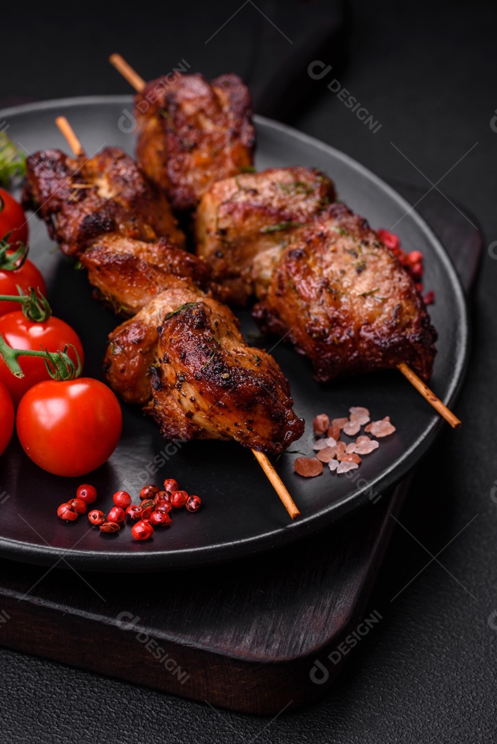 Deliciosos espetos de frango, peru ou porco grelhados com sal, especiarias e ervas no fogo sobre um fundo escuro de concreto