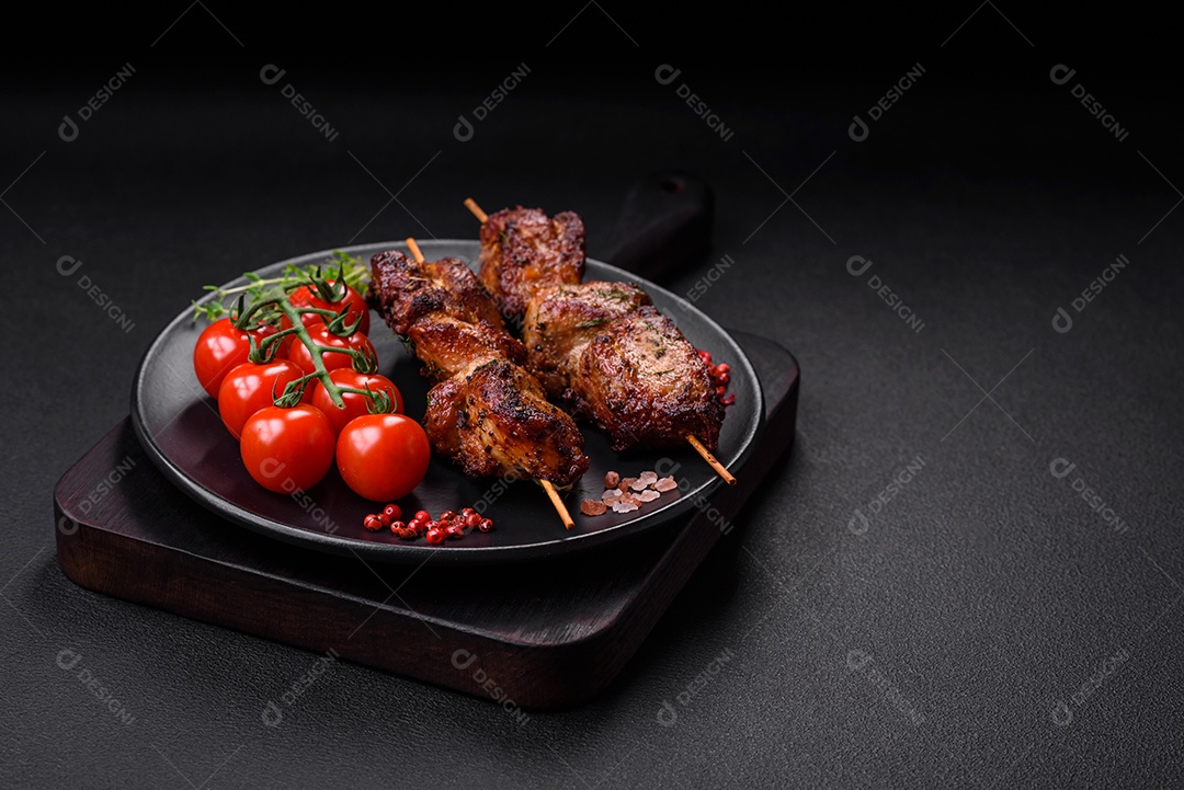 Deliciosos espetos de frango, peru ou porco grelhados com sal, especiarias e ervas no fogo sobre um fundo escuro de concreto