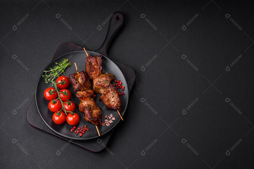 Deliciosos espetos de frango, peru ou porco grelhados com sal, especiarias e ervas no fogo sobre um fundo escuro de concreto