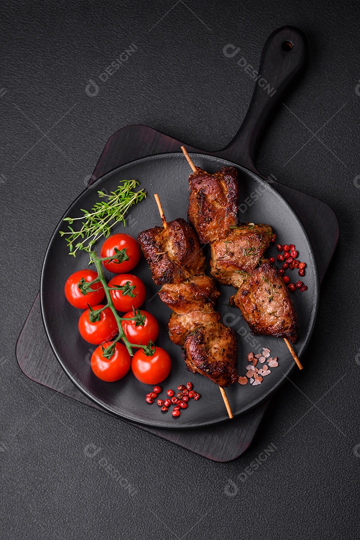 Deliciosos espetos de frango, peru ou porco grelhados com sal, especiarias e ervas no fogo sobre um fundo escuro de concreto