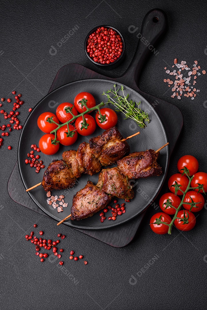 Deliciosos espetos de frango, peru ou porco grelhados com sal, especiarias e ervas no fogo sobre um fundo escuro de concreto