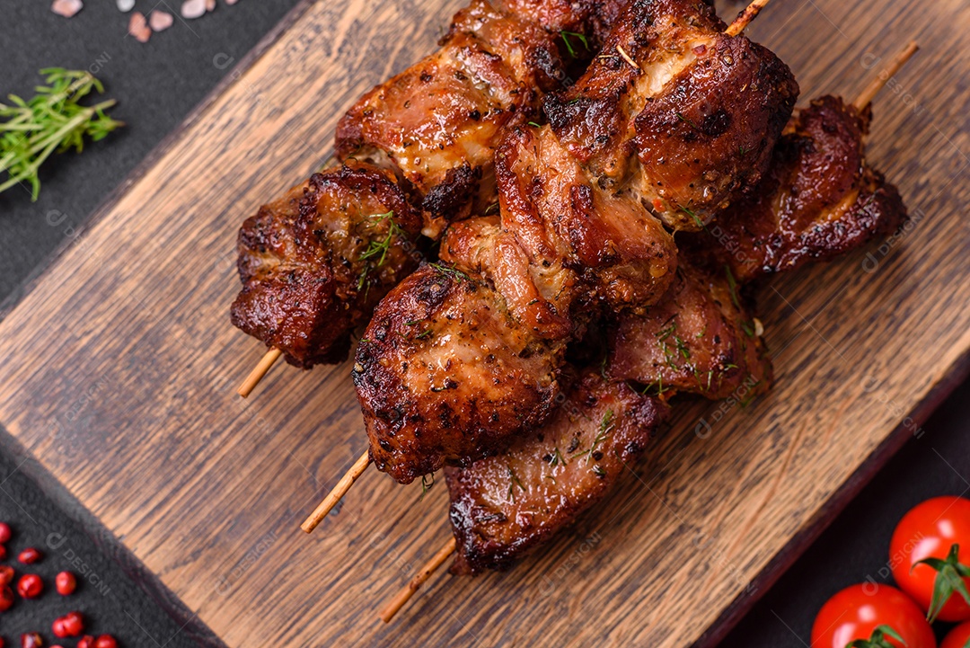 Deliciosos espetos de frango, peru ou porco grelhados com sal, especiarias e ervas no fogo sobre um fundo escuro de concreto