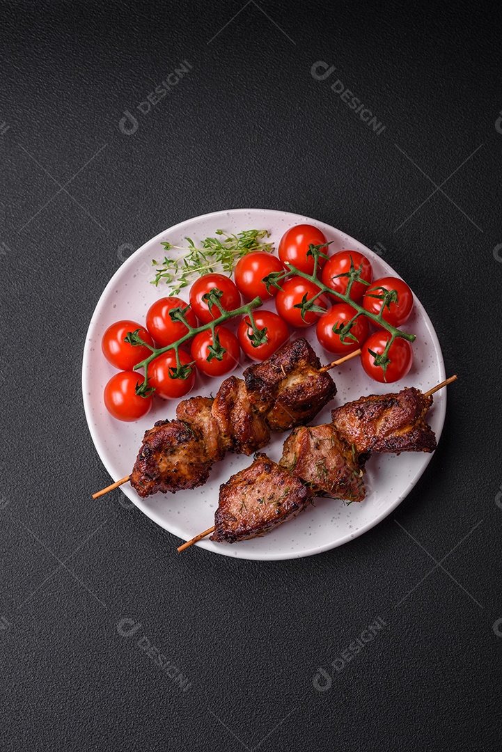 Deliciosos espetos de frango, peru ou porco grelhados com sal, especiarias e ervas no fogo sobre um fundo escuro de concreto