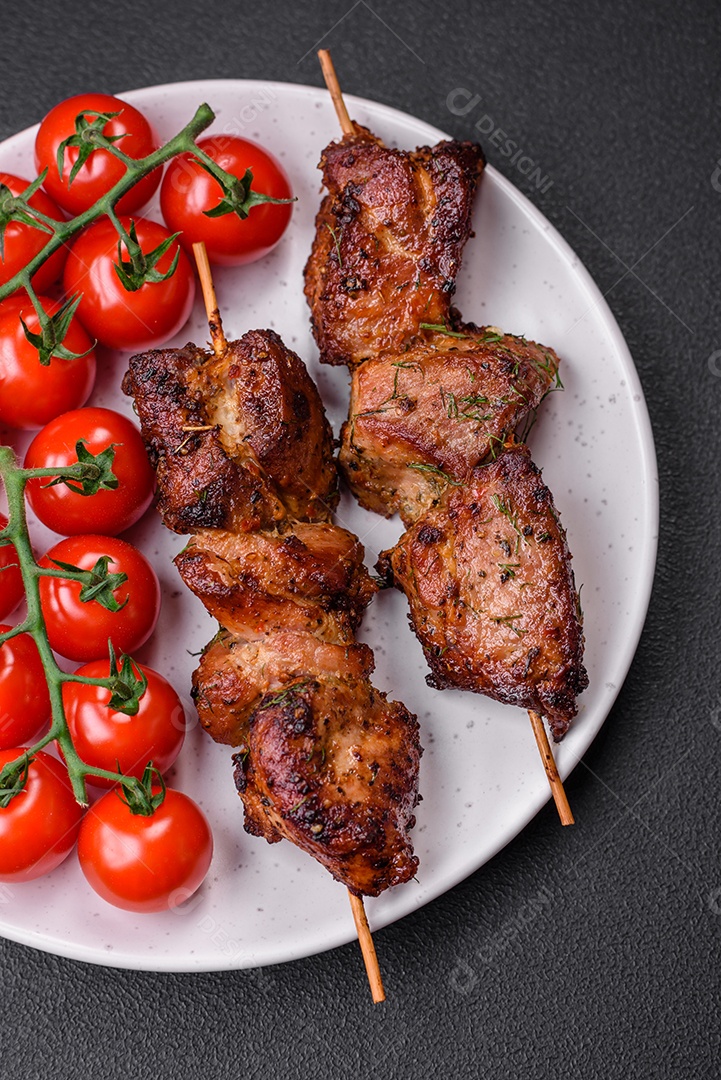 Deliciosos espetos de frango, peru ou porco grelhados com sal, especiarias e ervas no fogo sobre um fundo escuro de concreto