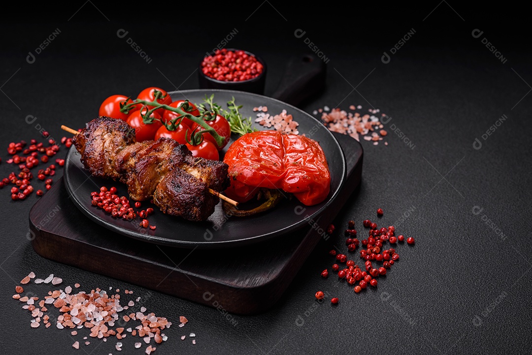 Deliciosos espetos de frango, peru ou porco grelhados com sal, especiarias e ervas no fogo sobre um fundo escuro de concreto