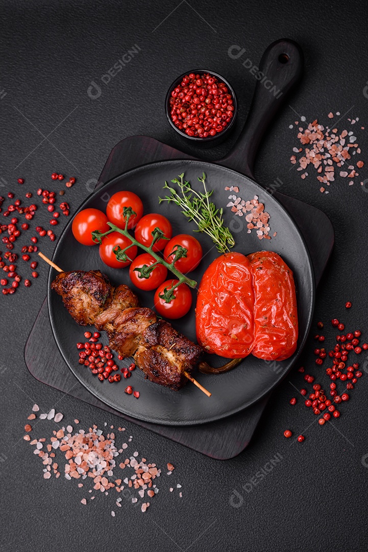 Deliciosos espetos de frango, peru ou porco grelhados com sal, especiarias e ervas no fogo sobre um fundo escuro de concreto