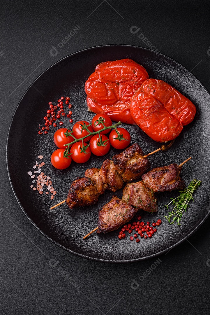 Deliciosos espetos de frango, peru ou porco grelhados com sal, especiarias e ervas no fogo sobre um fundo escuro de concreto