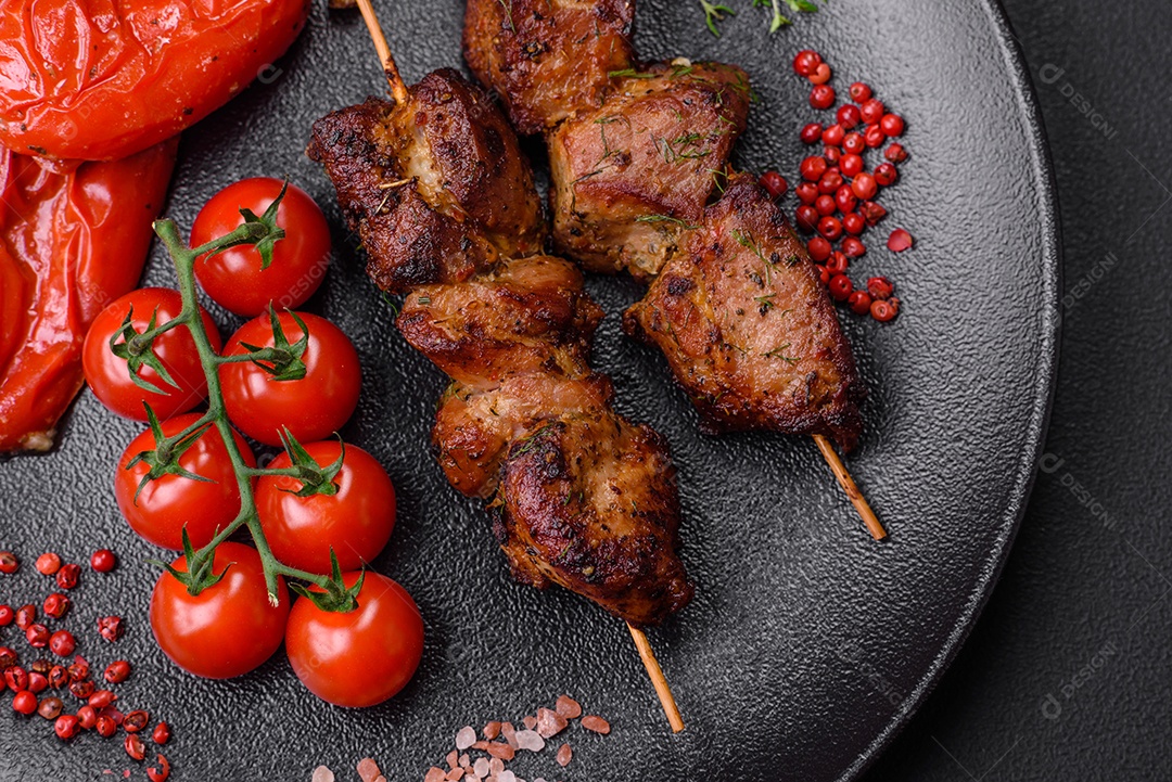 Deliciosos espetos de frango, peru ou porco grelhados com sal, especiarias e ervas no fogo sobre um fundo escuro de concreto