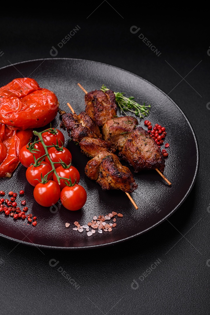 Deliciosos espetos de frango, peru ou porco grelhados com sal, especiarias e ervas no fogo sobre um fundo escuro de concreto